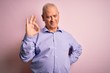 © Krakenimages.com - Middle age handsome hoary man wearing casual shirt standing over pink background smiling positive doing ok sign with hand and fingers. Successful expression.
