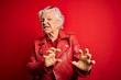 © Krakenimages.com - Senior beautiful grey-haired woman wearing casual red jacket and sunglasses disgusted expression, displeased and fearful doing disgust face because aversion reaction. With hands raised