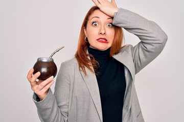 Canvas Print - Young beautiful redhead woman drinking argentina mate beverage over white background stressed with hand on head, shocked with shame and surprise face, angry and frustrated. Fear and upset for mistake.