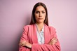 Young beautiful brunette woman wearing jacket standing over isolated pink background skeptic and nervous, disapproving expression on face with crossed arms. Negative person.