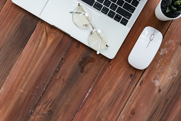 Top view of Computer laptop plant and glasses on wooden desk for work from home,Top view with copy space,Business flat design,Work from home Concept