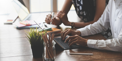 cropped image of marketing team holding a stylus pen and typing on computer tablet with keyboard cas
