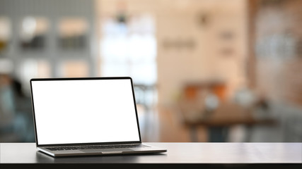 Blank screen computer laptop putting on smooth surface working desk over comfortable living room as background.