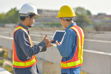 Wall Mural - Two engineer talking communication use tablet inspection at construction site