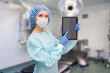Female doctor in protective suit: medical mask, hat and robe. The woman uses a digital tablet and displays disease statistics on the screen.