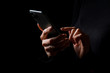 © Kaspars Grinvalds - Person holding in hands and typing on mobile phone, photo isolated on black background