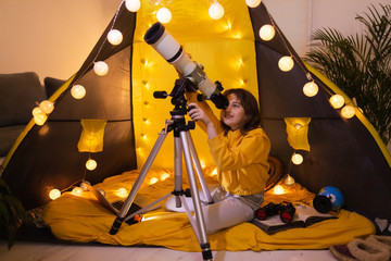 Wall Mural - small girl using telescope at home living room in a tent.