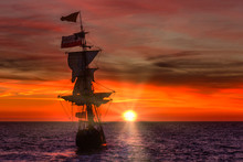 Antique Wooden Ship Leaving The Harbor Under A Bright Red Sunset Spring Time