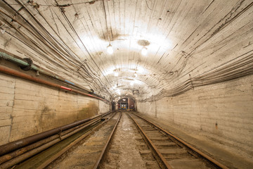 Underground gold mine tunnel with rails and light