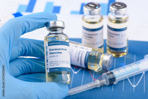 Coronavirus COVID-19 vaccine vial and injection syringe in scientist hands concept. Research for new novel corona virus vaccination immunization drug.