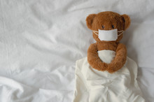 Teddy Bear Toy Wearing Mask Sleep On Bed. Stay Home Away From Virus Concept.