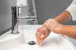 Hand washing lather soap rubbing wrists handwash step woman rinsing in water at bathroom faucet sink. Wash hands for COVID-19 spreading prevention. Coronavirus pandemic outbreak.