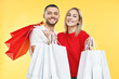© GVS - Young happy couple holding shopping bags in hands isolated over yellow background