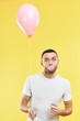 © GVS - Young funny man blowing chewing gum bubble and holding pink air balloon