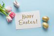 © svetlana_cherruty - Easter greeting card with pink tulips, bunny, golden eggs on blue. Text - Happy Easter. Top view.