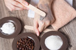 © NataliSam - A woman puts a spatula of coffee homemade scrub on her hand. SPA, beauty. Ingredients for making scrub, coffee beans, sugar, cream. Skin care.  Moisturizing, exfoliating, peeling. Home Cosmetics, Eco