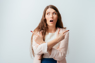 long-haired beautiful young brunette woman confused, holding fingers in different directions, isolated on a white background