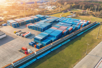 Aerial view of container loading and unloading at sunset. Top view of containers at logistics terminal for export and import, train, railroad. Business. Freight transportation containers on railway