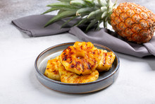 Heap Of Grilled Pineapple Slices On Gray Plate On Concrete Background.
