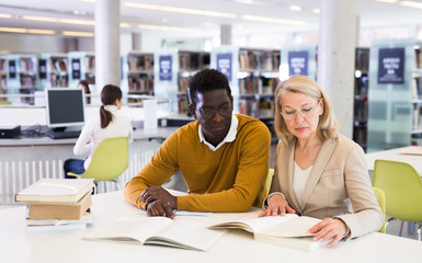 Wall Mural - Two adult students studying together in public library