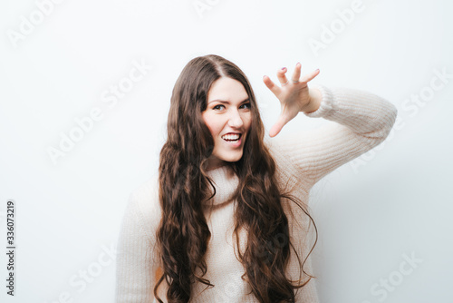 Photographie cheerful brunette girl growls like a tiger on a white background