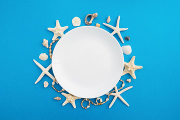 Wall Mural - White empty plate with sea decoration shells and stars around it over blue background