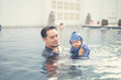 © grooveriderz - Asian father swimming with cute adorable baby in swimming pool. Smiling dad and little child, newborn son having fun together.