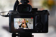© artiemedvedev - Display of camera recording video blog for blonde beauty blogger woman with make-up at home studio. Influencer vlogger girl live streaming cosmetics masterclass. Online learning and marketing concept.
