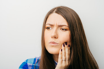 Wall Mural - Teen woman pressing her bruised cheek with a painful expression as if she's having a terrible tooth ache.