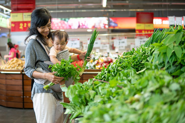 Wall Mural - beautiful asian woman carrying her baby while shopping in grocery store