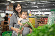 © Odua Images - beautiful asian woman carrying her baby while shopping in grocery store