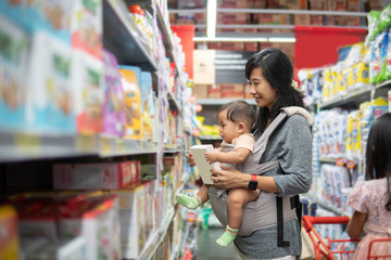 Wall Mural - asian mother buying baby product while carrying her daughter