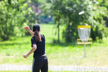 Young Woman Playing Flying Disc Sport Game In The Park