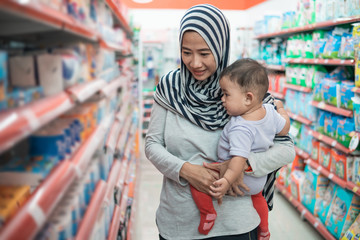 Wall Mural - muslim asian mother buying baby product while carrying her daughter