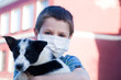 Young boy wear protection mask and holding puppy outdoors. To prevent pathogens caused by sick dog. Health care with pet and natural. Covid-19 virus.