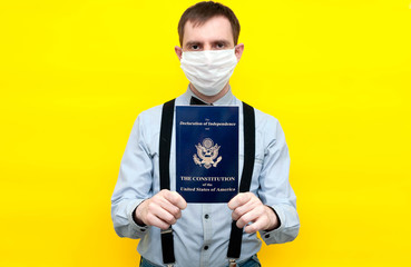 man in white medical face mask usa constitution and independence declaration in front of yellow background with copy space