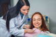 © Maxim - Young beautiful woman with beautiful white teeth sitting on a dental chair. Portrait of a woman with toothy smile sitting during examination at the dental office