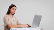 © South House Studio - Mid shot of pretty female, she seats at the table and works freelance at her home computer, isolated over white