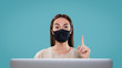 © South House Studio - Front shot of woman in front of her laptop, wear mask and pointing her finger up