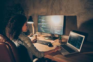 Wall Mural - Back rear spine view photo focused skilled afro american software developer sit table desk evening start-up office use computer work binary web code testing operating system in workstation