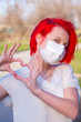 Red hair teenage girl wearing a medical mask shows the heart symbol love to fight and strong encourage health care from Covid 19