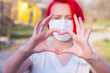 Red hair teenage girl wearing a medical mask shows the heart symbol love to fight and strong encourage health care from Covid 19
