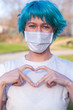 Blue hair young woman wearing a medical mask shows the heart symbol love to fight and strong encourage health care from Covid 19