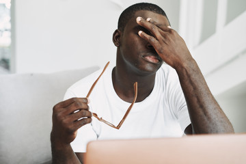 A man of African appearance at home in front of a laptop relaxing