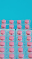 Pink tablets. Pills on a blue background, medical drugs.