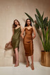 © indiraswork - Two fashion model brunette hair wear green  brown silk dress sandals shoes accessory clothes date party walk interior journey summer collection plant flowerpot stairs beautiful woman tan skin friends.