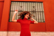 © Westend61 - Portrait of happy woman with red dress, dancing in front of a red wall