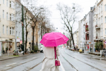 Rear View Of A Woman With Pink Umbrella Walking On Street