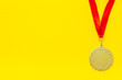 Gold medal with red ribbon - winner, success concept - on yellow background top view copy space