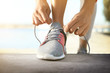 Sporty woman tying shoelaces outdoors on sunny day, closeup